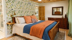 A bedroom with a wooden ceiling fan, a bed with multiple pillows, a dresser, and a mirror.