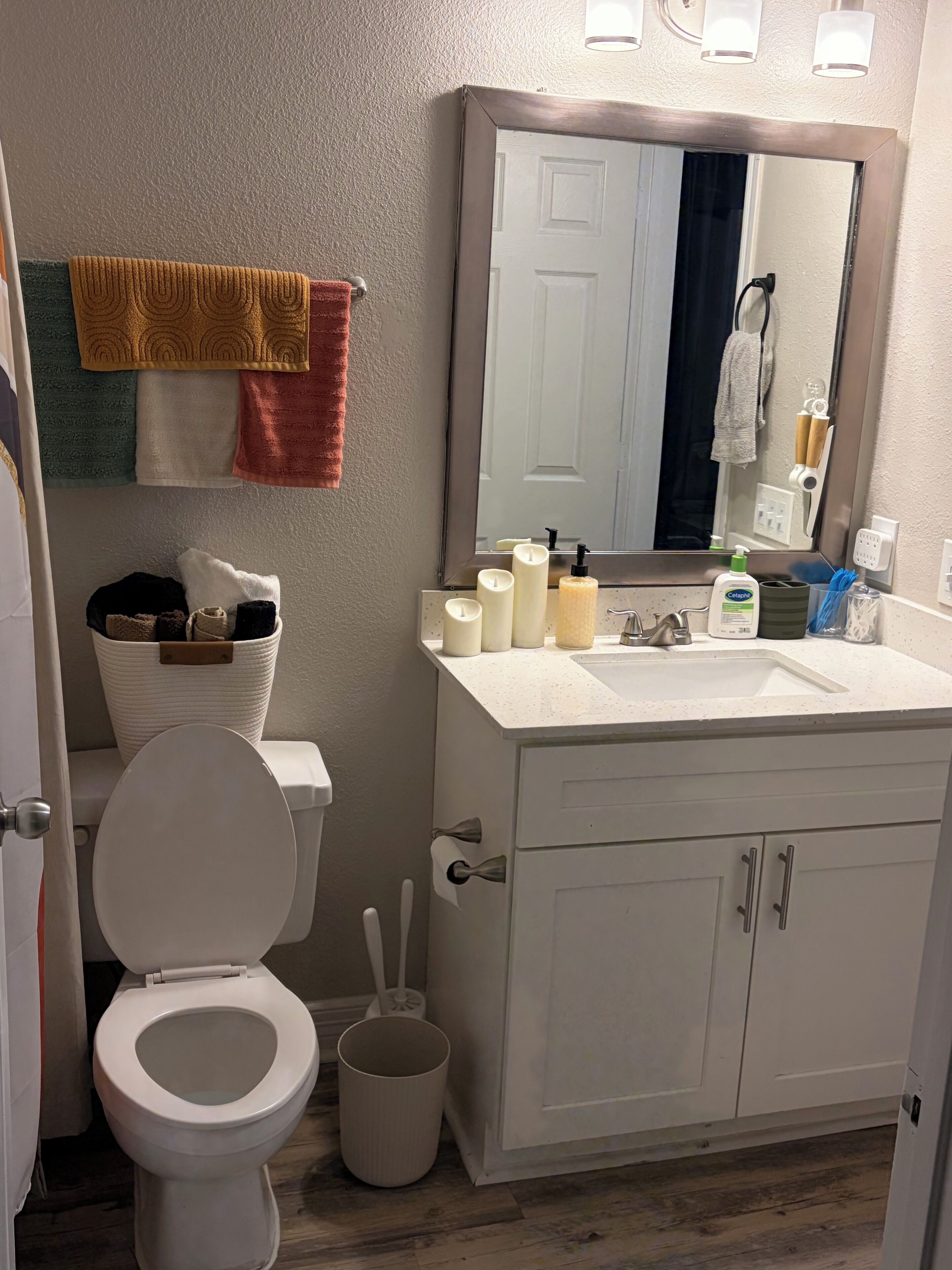 A bathroom with a toilet, sink, mirror, and towels.