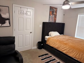 A bedroom with a bed, a chair, a door, and a ceiling fan. - Just 6 mins from
Braves Stadium , 8 miles from Benz Stadium & State Farm Arena (Atlanta)