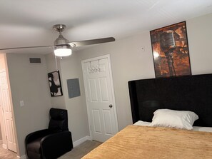 A bedroom with a bed, a ceiling fan, a door, a chair, and a poster on the wall. - Just 6 mins from
Braves Stadium , 8 miles from Benz Stadium & State Farm Arena (Atlanta)