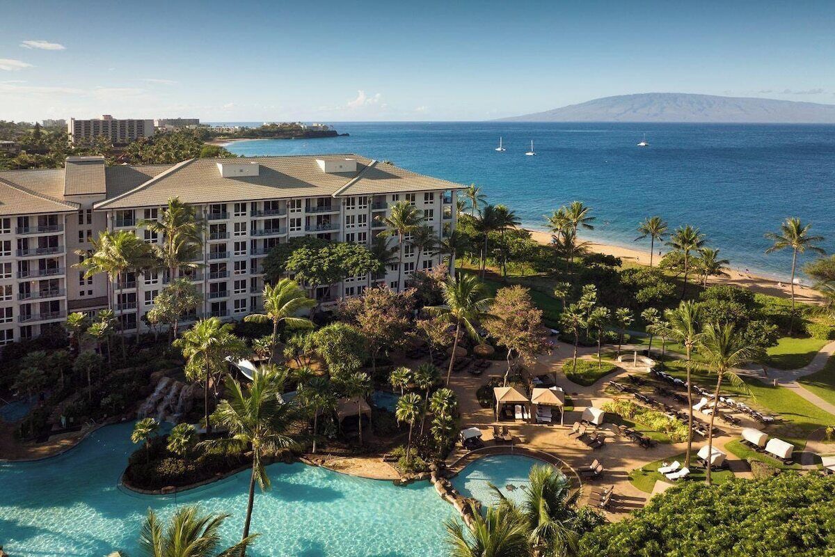 Ein Resort mit Pool, Palmen und Blick aufs Meer.