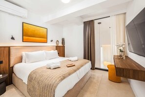 Quarto de hotel com cama, escrivaninha, televisão e um quadro na parede.
