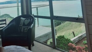 Habitación con un ventanal que ofrece vistas a un lago y colinas lejanas.