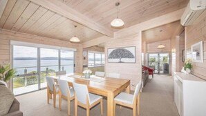 Un interior moderno con una mesa de comedor de madera, sillas y vista al mar.