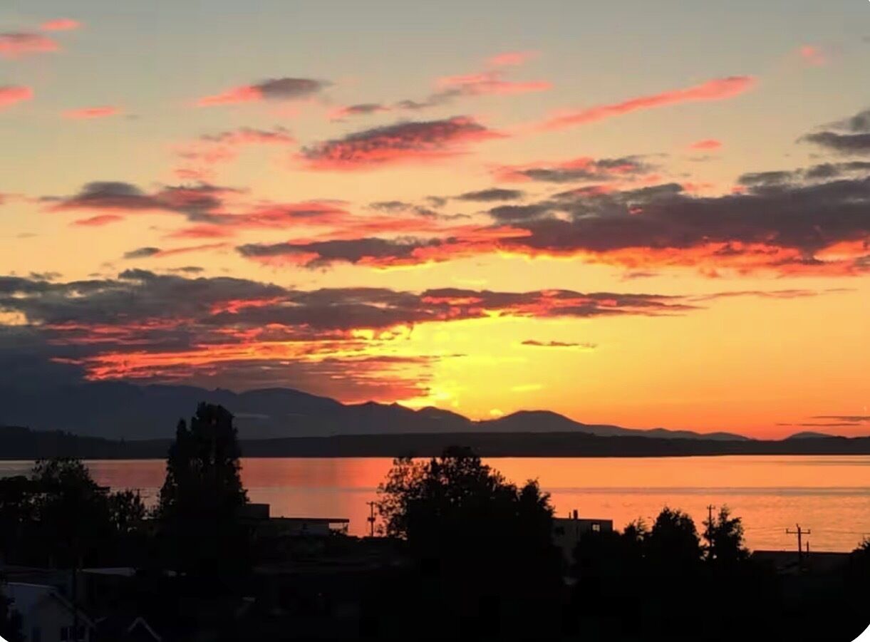 Un tramonto su un corpo d'acqua con montagne sullo sfondo.