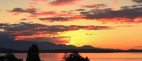 Un tramonto su un corpo d'acqua con montagne sullo sfondo.