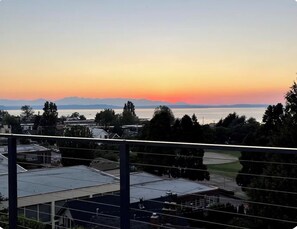 Área residencial com vista para a água e montanhas ao pôr do sol.