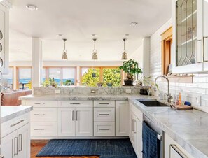 A modern kitchen with white cabinetry, a marble countertop, and pendant lighting. - Seattle Luxury VIEW House, Walk to Beach, Park, Forest, Tennis Court (Seattle)
