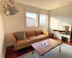 A living room with a leather sofa, a wooden coffee table, and a desk with a chair. - Seattle Luxury VIEW House, Walk to Beach, Park, Forest, Tennis Court (Seattle)