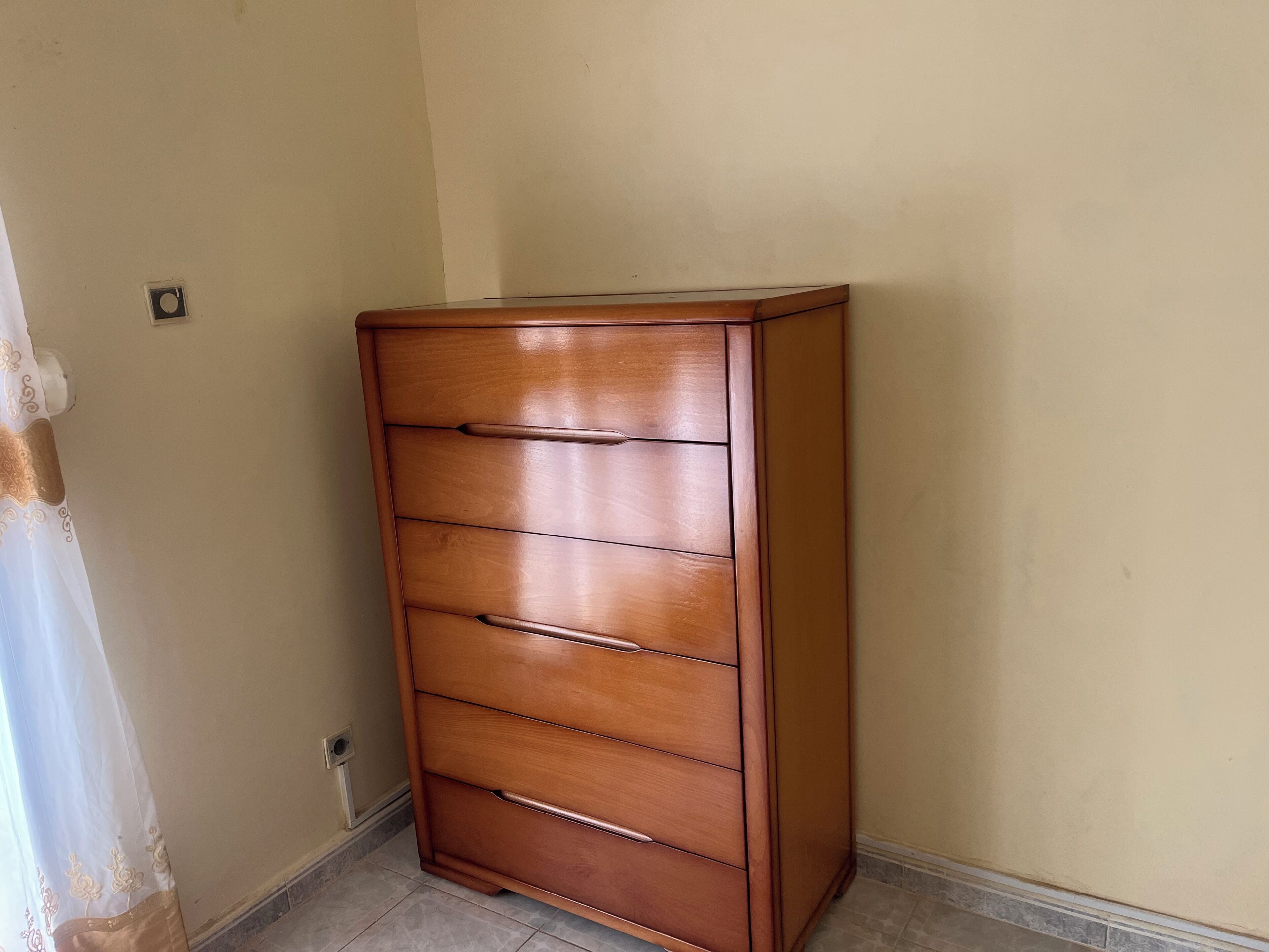Un aparador de madera con varios cajones frente a una pared lisa.