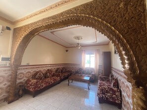 A room with a patterned sofa, a wooden coffee table, and an ornate archway. - Family Apartment in Aïn El Turk – 7-minute walk to the beach (Ain turk)