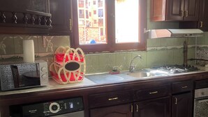 Una cucina con lavatrice, forno a microonde, lavello e mobili in legno.