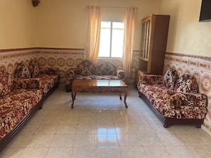 Una sala de estar con sofás estampados, una mesa de centro de madera y un aparador.
