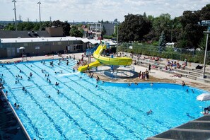A large outdoor swimming pool with multiple lanes and a central water slide.