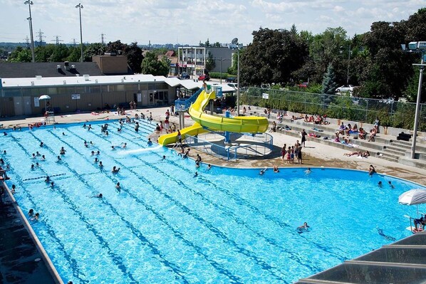 Uma grande piscina ao ar livre com várias pistas de natação e um toboágua central.