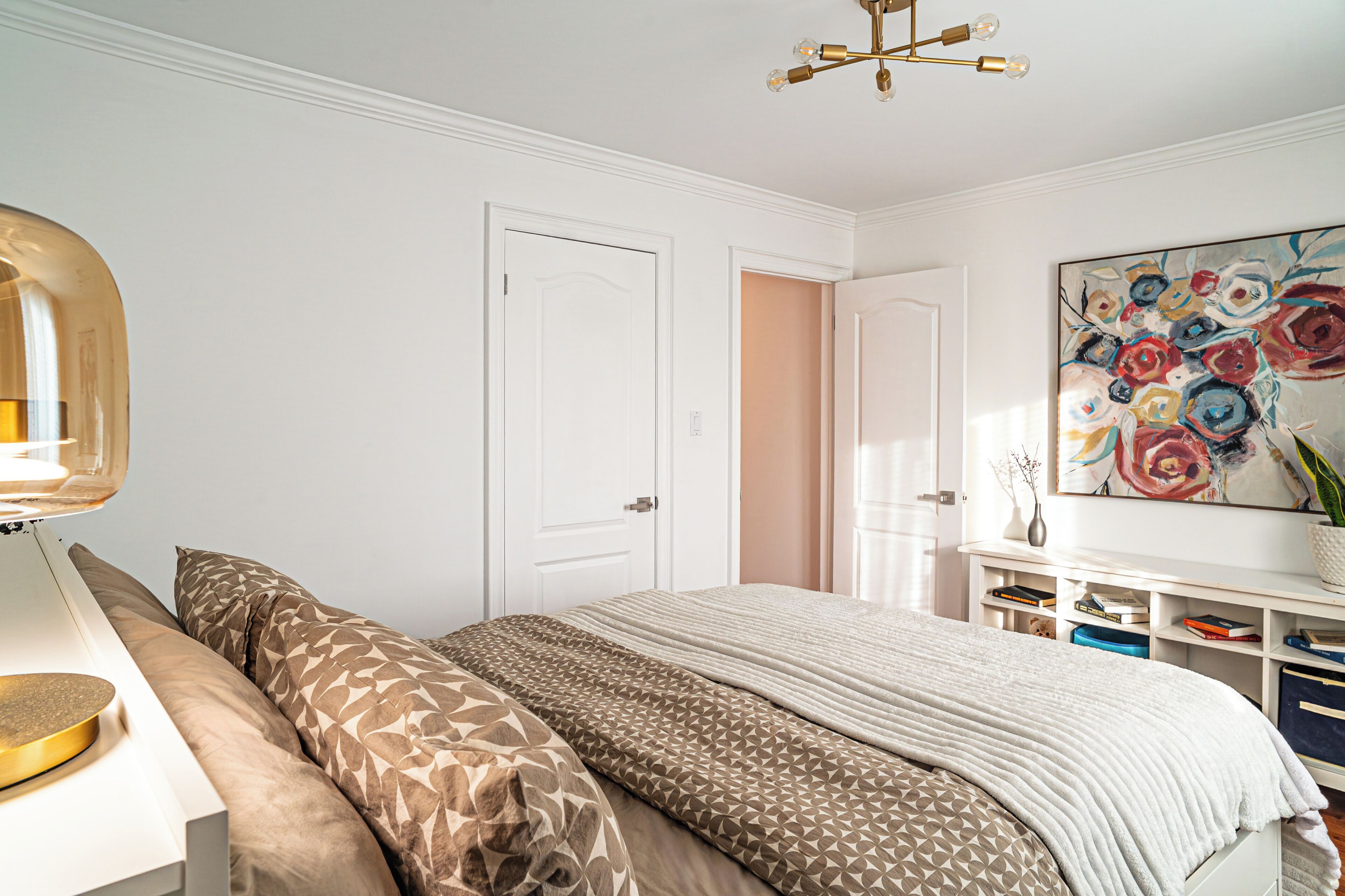 Une chambre à coucher avec un lit, des tables de chevet, une lampe, un tableau et une bibliothèque.