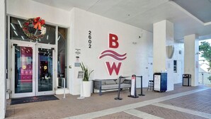 A hotel entrance with a glass door, a red and white logo, and a number '2602' on the wall. - Studio with Balcony, Pool & Gym (Hallandale Beach)