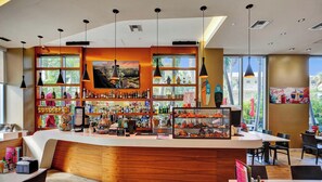 Um bar moderno com balcão curvo, várias prateleiras de garrafas e vista para palmeiras lá fora.