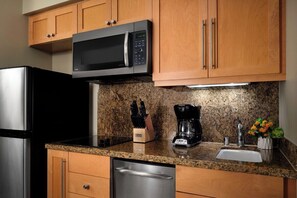 A kitchen with wooden cabinets, a stainless steel refrigerator, a black microwave, a coffee maker, and a dish soap bottle. - 2 Bedroom Villa at Westin Kaʻanapali Resort (Lahaina)