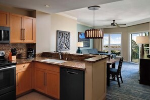 A kitchen with granite countertops, wooden cabinets, a dishwasher, and a dining area with a table and chairs. - 2 Bedroom Villa at Westin Kaʻanapali Resort (Lahaina)