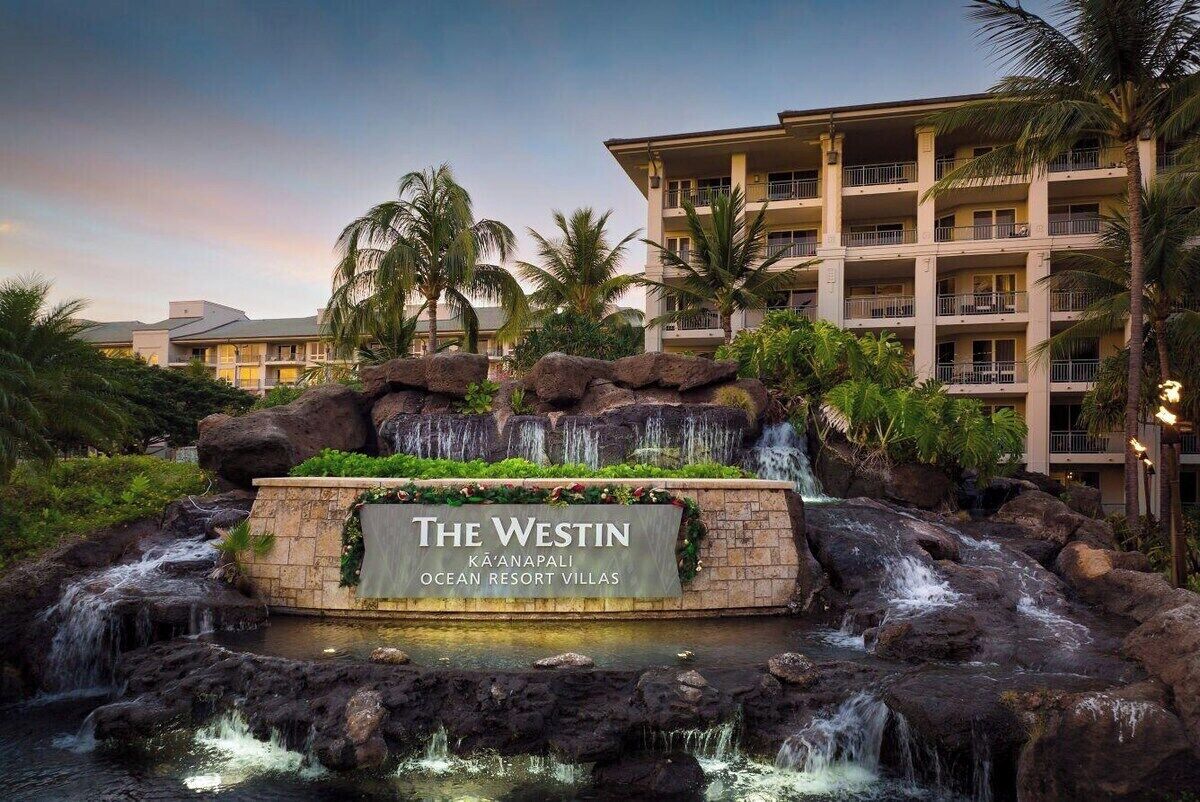 Ein Resort mit einem Wasserfall, Palmen und einem Schild mit der Aufschrift 'The Westin Kau'Anapali Ocean Resort Villas'.