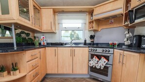 A kitchen with wooden cabinets, a stove, and a window. - Balwen (Mold)