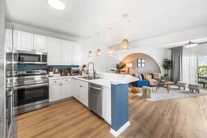 A modern kitchen with stainless steel appliances, white cabinetry, and a blue accent wall. - 3BR/3Bath, Steps to Private Beach Access! (Destin)