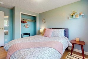 A bedroom with a bed, a chair, a bedside table, and a shelf with decorative items. - 3BR home with enclosed yard, grill, W&D, fast WiFi (Dundee)