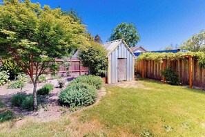 A backyard with a wooden fence, a shed, and a tree. - 3BR home with enclosed yard, grill, W&D, fast WiFi (Dundee)