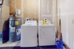 A laundry area with two washing machines, a water heater, and cleaning supplies.