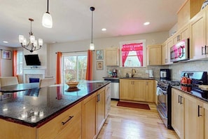 A modern kitchen with wooden cabinets, a granite countertop, and stainless steel appliances.