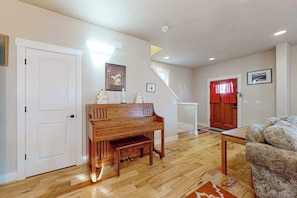 A room with a wooden piano, a sofa, and a staircase leading to another level.