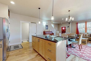 A modern kitchen with a central island, wooden cabinets, and pendant lighting.