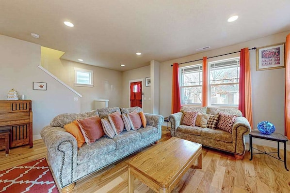 A living room with two sofas, a coffee table, a wooden cabinet, and a staircase.