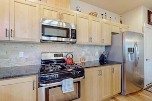 A kitchen with a stainless steel stove, microwave, and refrigerator.