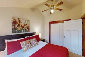 A bedroom with a large bed, a ceiling fan, a painting on the wall, and a set of white doors. - Lovely 3BR Oregon Wine Country - Washer & Dryer (McMinnville)