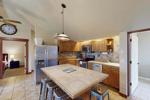 A modern kitchen with a central island, stainless steel appliances, and wooden cabinets.