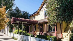 A two-story building with a covered porch and a sign reading 'BISTRO MAISON.'