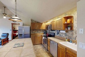 A kitchen with wooden cabinets, a refrigerator, a stove, and a sink.
