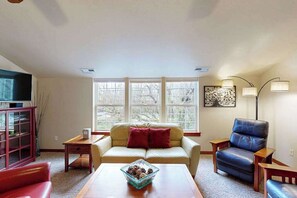 A living room with a sofa, a coffee table, a television, and a window with a view. - Lovely 3BR Oregon Wine Country - Washer & Dryer (McMinnville)