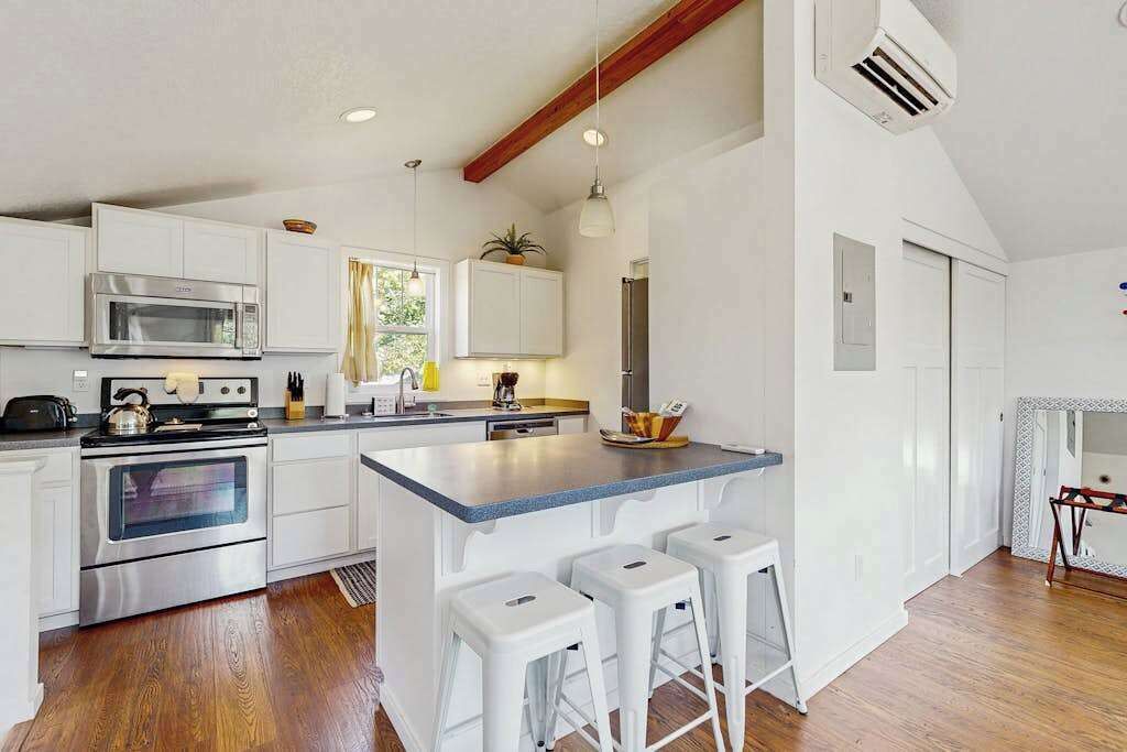 A modern kitchen with white cabinetry, stainless steel appliances, and a central island with bar stools.