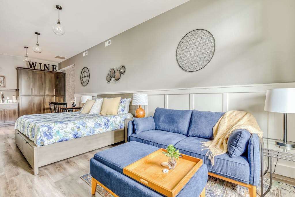 Een slaapkamer met een bed, een bank, een bijzettafeltje en een muur met een 'WINE' bord.