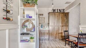 Ein Essbereich mit Holztisch und -stühlen, einem weißen Schrank mit Weinflaschen und einem Schrank mit der Aufschrift 'WINE'.
