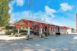 Um edifício com área externa coberta, uma placa com a inscrição 'LITE & PACIFIC' e um estacionamento.