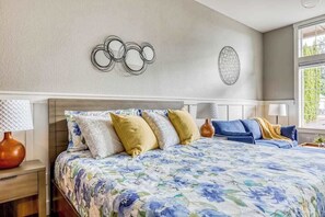 A bedroom with a large bed, a nightstand, a lamp, and wall art. - Updated Studio Oregon Wine Country - Kitchenette (McMinnville)