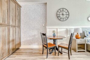 A dining area with a round table, two chairs, a wall clock, and a patterned wallpaper. - Updated Studio Oregon Wine Country - Kitchenette (McMinnville)