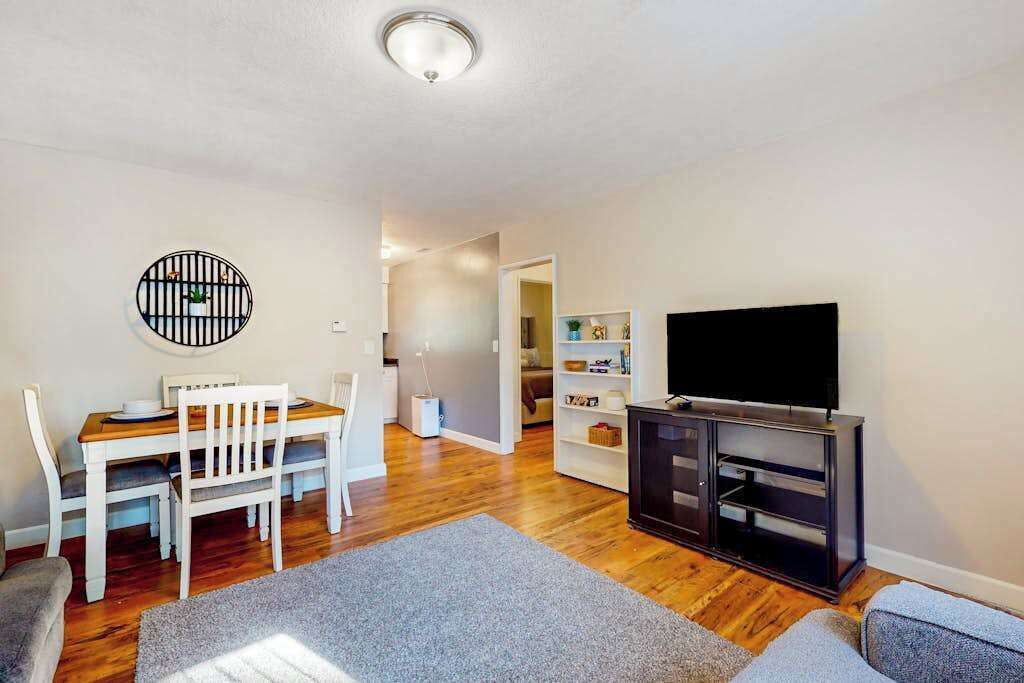 A living room with a dining table, chairs, a TV, and a bookshelf.