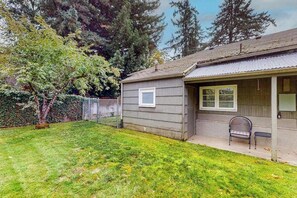A residential property with a detached garage, a covered porch with a bench, and a well-maintained lawn. - 2BR peaceful getaway with patio & W&D - near river (Milwaukie)