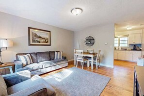 A living room with a sofa, chairs, a dining table, and a kitchen in the background. - 2BR peaceful getaway with patio & W&D - near river (Milwaukie)