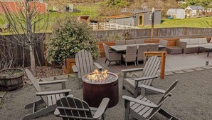 En uteplats med Adirondack-stolar, en eldstad och en terrass med utemöbler.